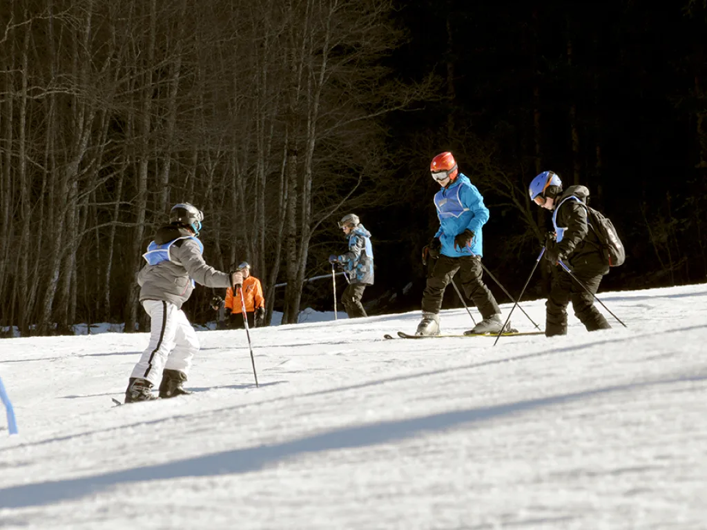 Skifahrende gehen über die Piste zum Lift.